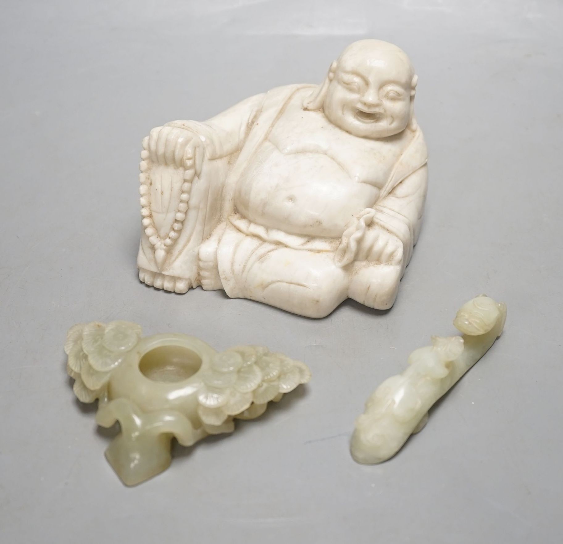 A Chinese celadon jade brushwasher, a bowenite jade belt hook and a soapstone figure of Budai, buddha 7.5 cms high.